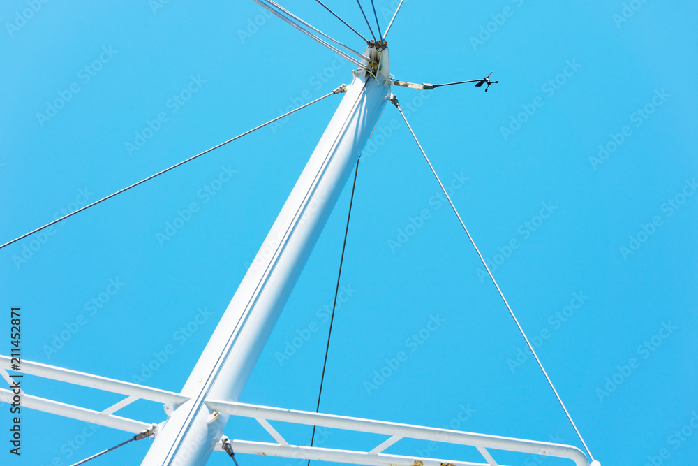The upper part of the white masts of yachts without sails against the blue cloudless sky The upper part of the white masts of yachts without sails against the blue cloudless sky
