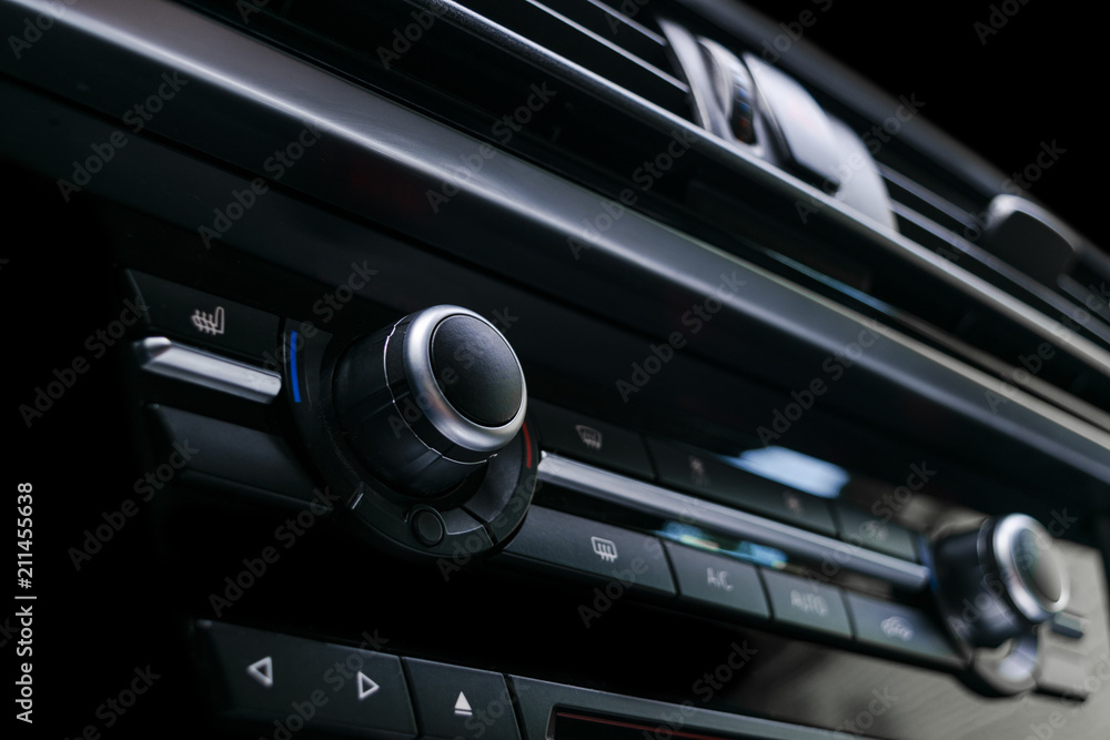 Air conditioning button inside a car. Climate control AC unit in the new car. Modern car interior details. Car detailing. Black perforated leather interior.