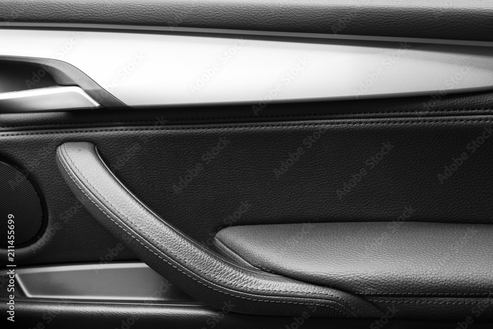 Door handle with Power window control buttons of a luxury passenger car. Black leather interior of the luxury modern car. Modern car interior details. Car detailing