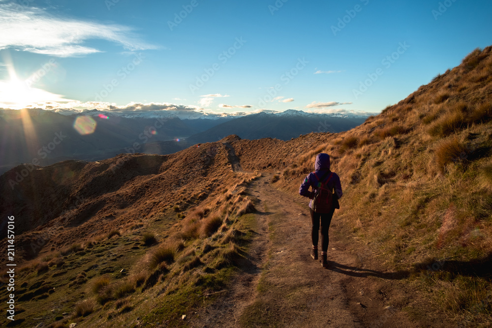 A hiker hiking on the beautiful track with a landscape of the mountains and Lake Wanaka. Roys Peak Track, South Island, New Zealand.