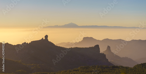 Silhouettes of Roque Nublo and Bentayga against sunset light. Pico de Teide on background. Gran Canaria, Canary islands, Spain