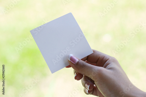 Hand hold white blank business card on green