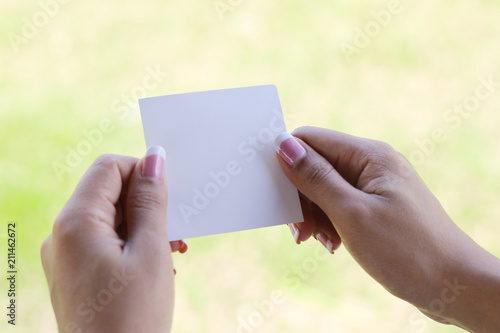 Hand hold white blank business card on green