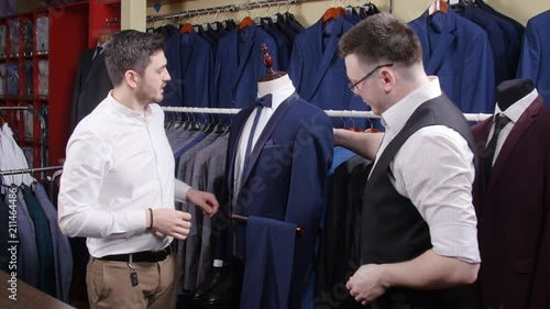 Man helps another try on a suit in a clothing store photo