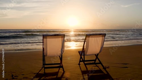 Two beach chairs on the beautiful sunset beach.