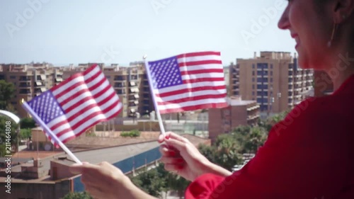 Red dressed woman waving USA national flag hand and celebrating a patriotic and american national holiday like 4ht of July, Flag day, national day or memorial day.Slow motion from 120 fps original cli photo