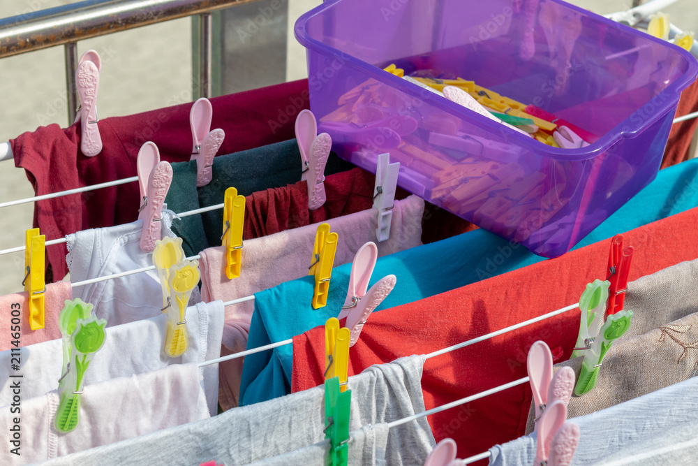 Kiste mit bunten Wäscheklammern oben auf einem voll behängten Wäscheständer  auf dem Balkon im Sommer Stock-Foto | Adobe Stock