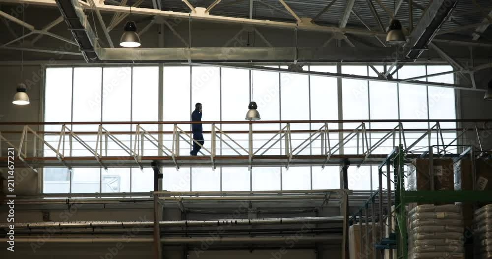 the engineer walks and talks by phone, near the window the engineer walks and talks by phone, near the window
