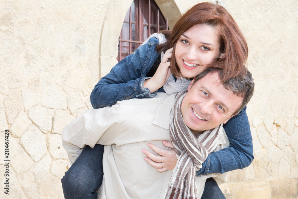 Woman having fun riding piggy back on man at ancient village tourism vacation day