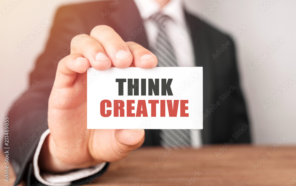 Businessman holding a card with text Think Creative Businessman holding a card with text Think Creative