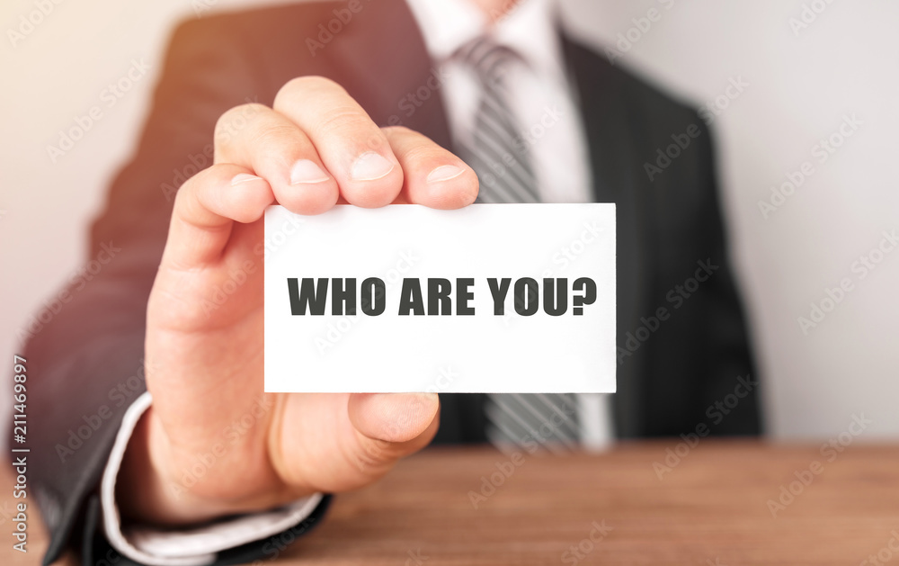 Businessman holding a card with text Who are you? Businessman holding a card with text Who are you?