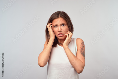 Horrible, stress, shock. Female half-length portrait isolated at pink studio. Young emotional surprised woman clasping head in hands. Human emotions, facial expression concept. Front