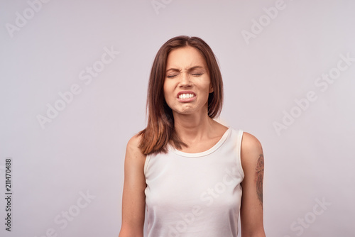 Picture of enraged dissatisfied young female grimacing, clenching teeth and making angry gesture while feeling furious at her cat that broke vase. Negative human emotions, feelings and reaction