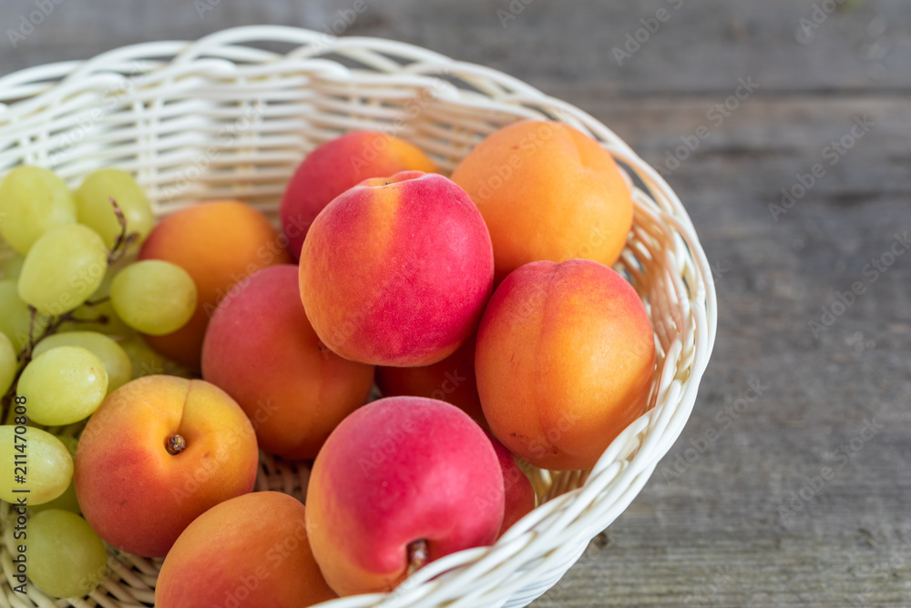 Delicious ripe apricots in a basket on wooden background.