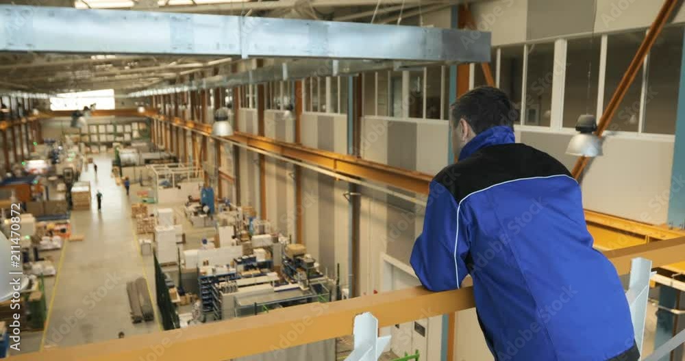 A supervisor or worker overlooks production of a large factory A supervisor or worker overlooks production of a large factory