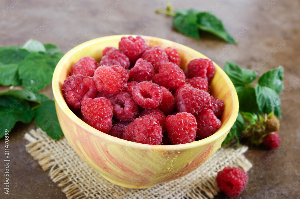 Fresh ripe tasty raspberries in a yellow ceramic bowl. Summer berries. Fresh ripe tasty raspberries in a yellow ceramic bowl. Summer berries.