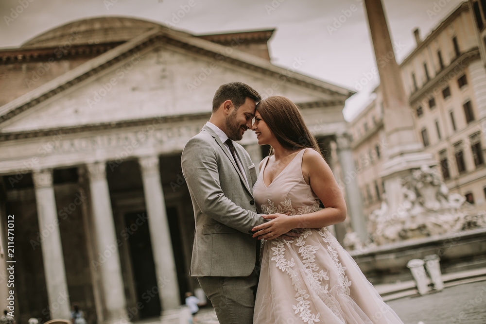 Naklejka premium Young newly married couple posing in Rome with beautiful and ancient architecture in the background