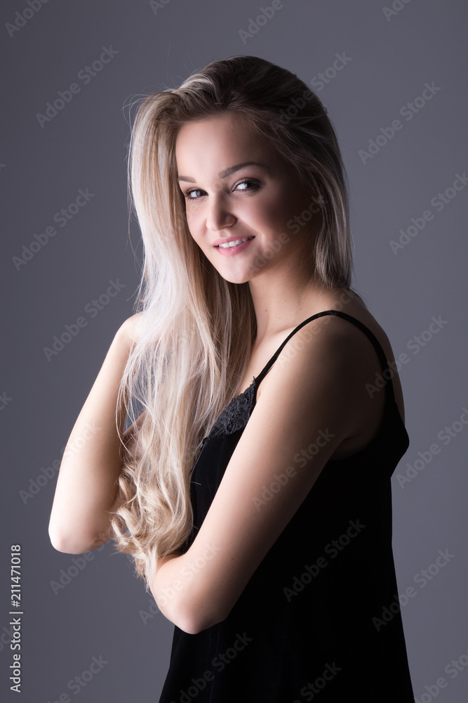 Fototapeta premium Close up studio portrait of a pretty blonde woman, smiling and looking at the camera