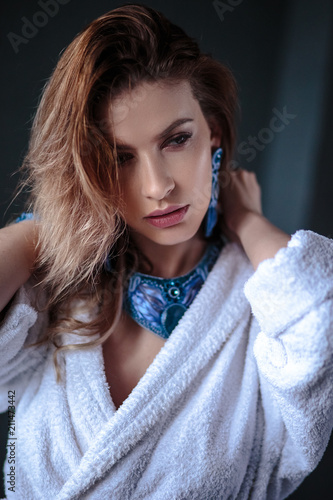 Young woman in a bathrobe and wet hair, fashion blue hand made jewelry, spa and care portrait, clean natural face, portrait on a background isolated
