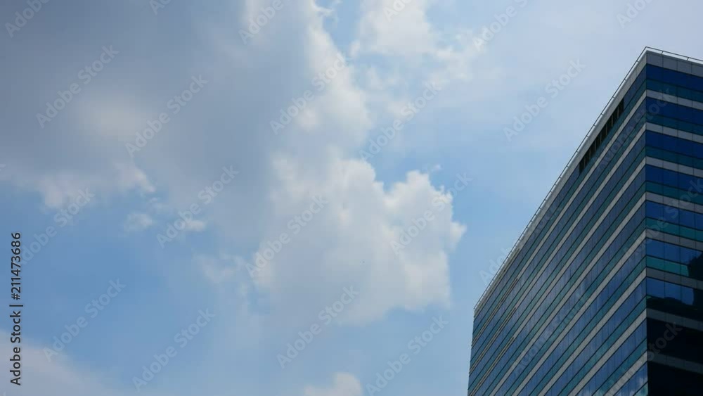 Exterior of glass office building reflection with blue sky and white cloud in a city with business, finance, construction and global warming concept Exterior of glass office building reflection with blue sky and white cloud in a city with business, finance, construction and global warming concept