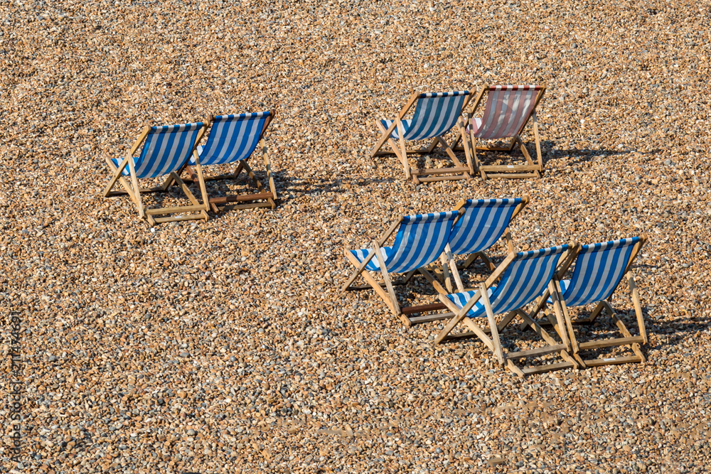 Looking down on vacant striped deckchairs on a pebble beach Looking down on vacant striped deckchairs on a pebble beach