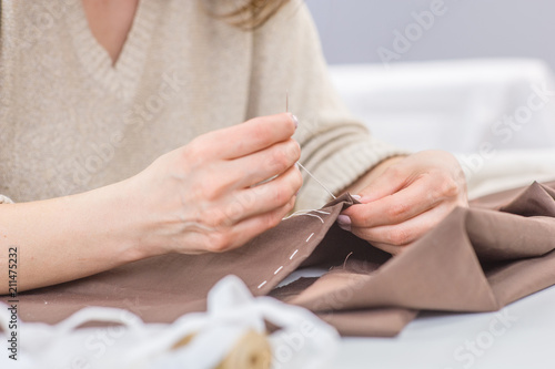 Close up hands sewing with a needle and thread. Hobby sewing as a small business concept