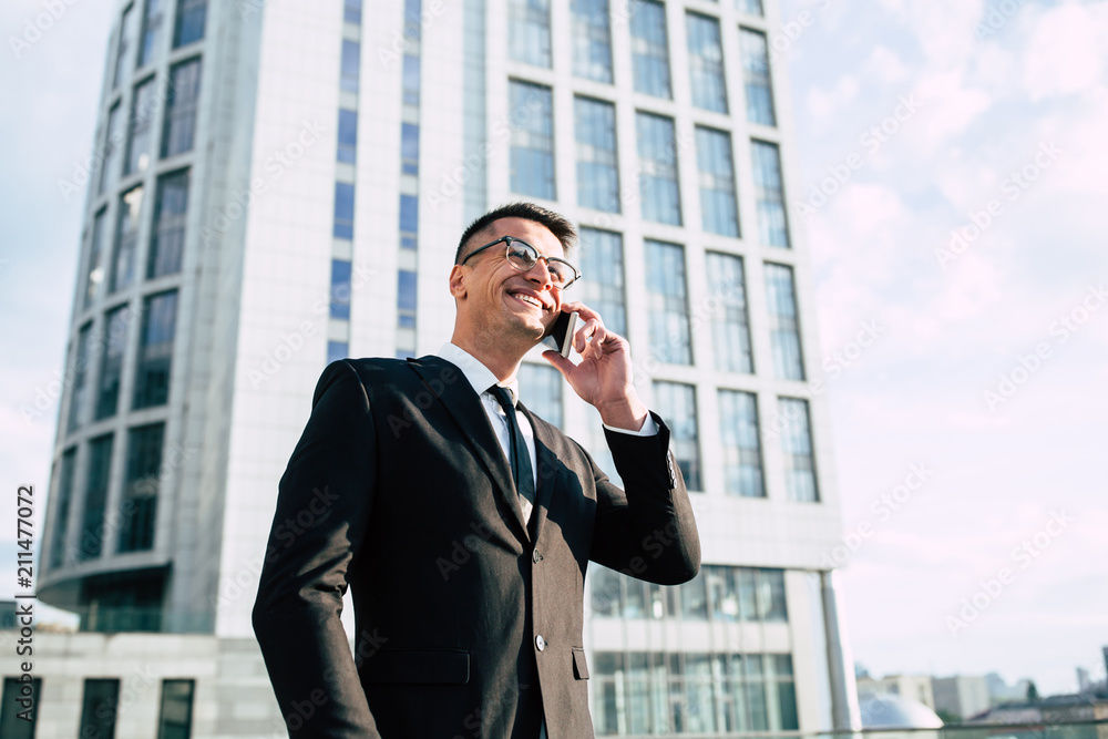 Handsome business man in full suit talking on phone outdoors Handsome business man in full suit talking on phone outdoors