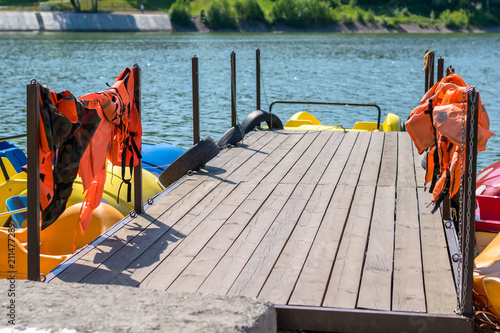 resort pier with life jackets for boats and catamarans on the lake photo