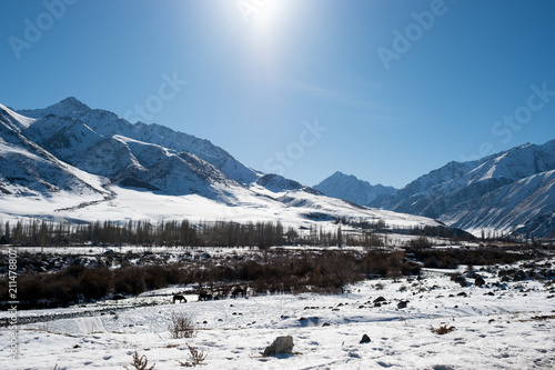 The river flows among the snowy mountains of Kyrgyzstan in the winter Sunny cloudless weather photo