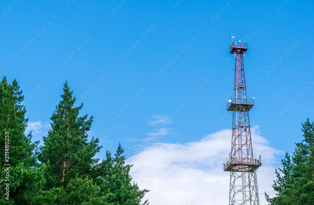 telecommunication tower with a parabolic antennas on a background of blue sky and clouds