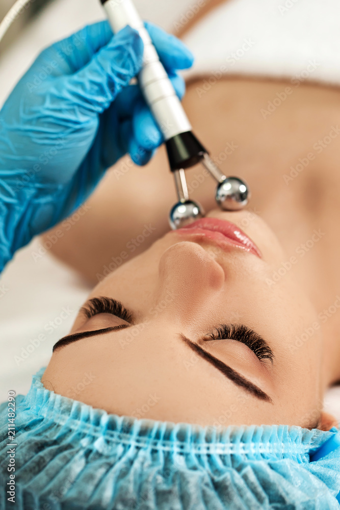 Naklejka premium Beautician makes cleaning of face in spa salon.