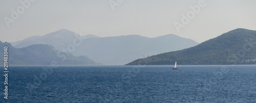 Lonely sailing boat. Seascape with the silhouette of a sailing ship in dramatic light. Aegina island, Greece, Saronic gulf