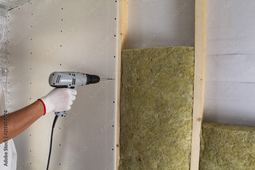 Ταπετσαρία Close-up of worker hand with electric screwdriver fastening drywall to wooden timber frame with insulation mineral rock wool staff