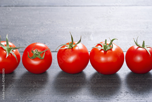 many tomatoes lined up on old black wooden table background