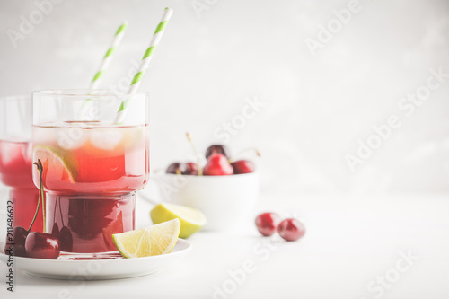 Cherry juice with ice and lime in a glass beaker, light background. White background.