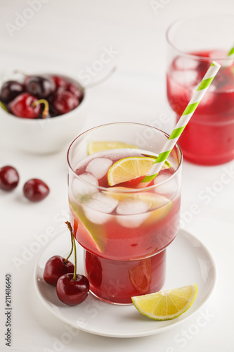 Cherry juice with ice and lime in a glass beaker, light background. White background.