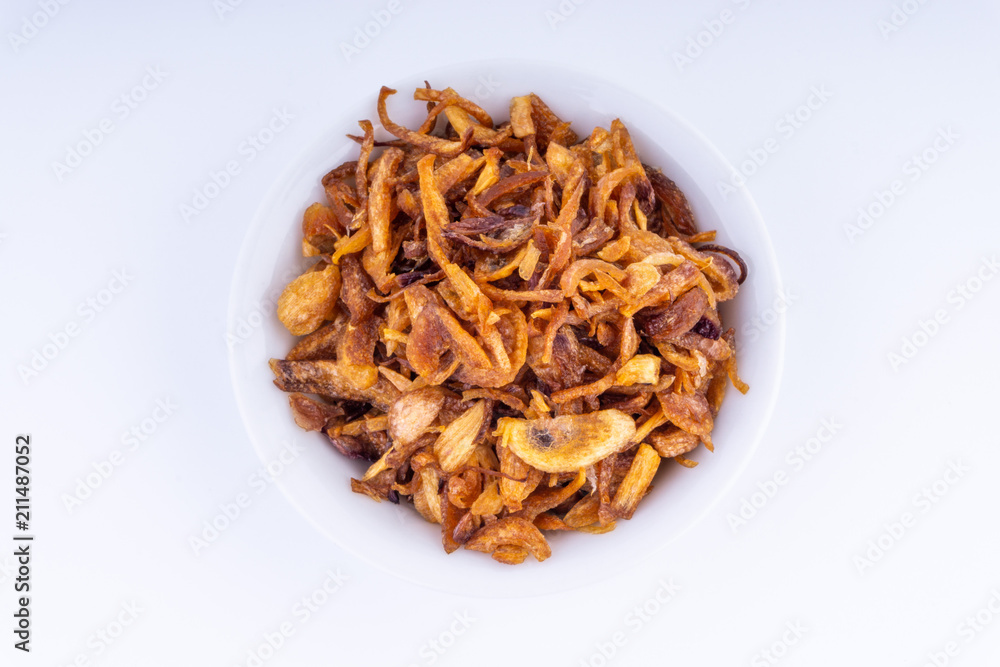 Deep fried shallots crisp / fried crispy onion flakes (bawang goreng) in white bowl over wooden background. Deep fried shallots crisp / fried crispy onion flakes (bawang goreng) in white bowl over wooden background.