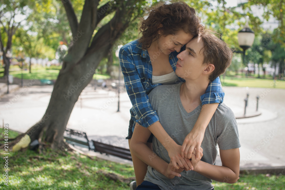 Young woman hugging and looking at the young man. Outdoor Young woman hugging and looking at the young man. Outdoor