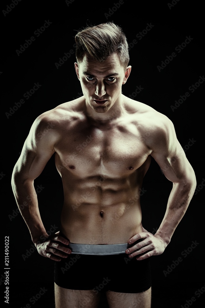 Fototapeta premium Handsome sporty young man in underwear posing on dark background