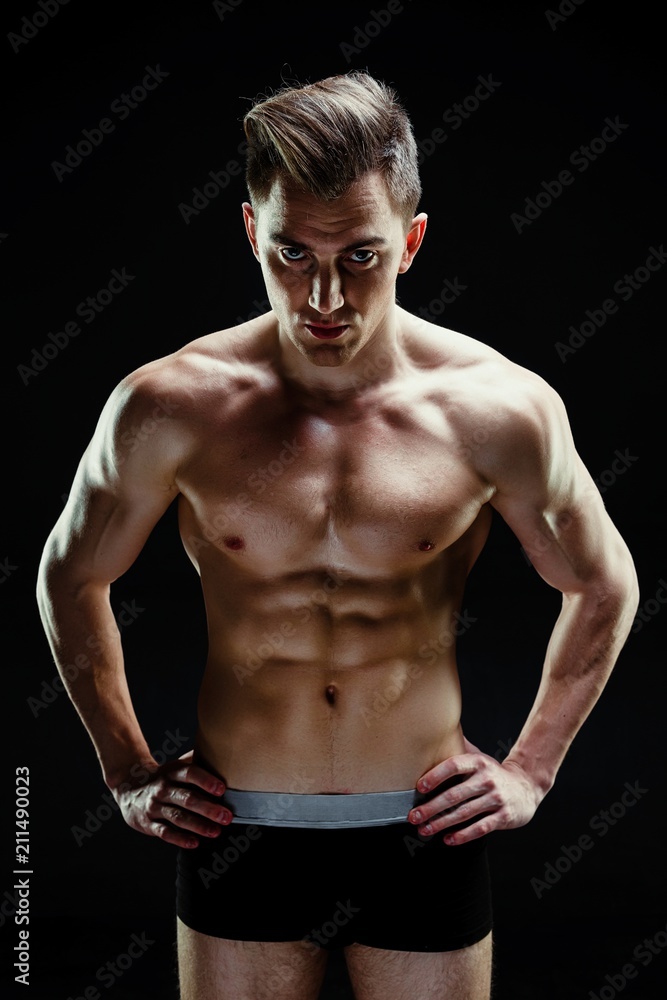 Fototapeta premium Handsome sporty young man in underwear posing on dark background