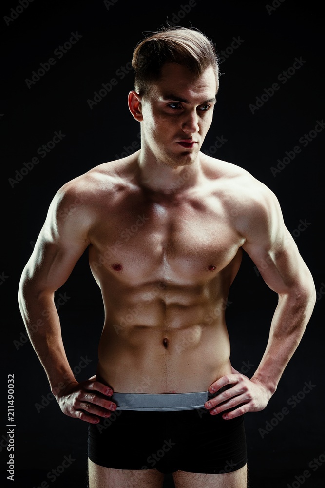 Handsome sporty young man in underwear posing on dark background Handsome sporty young man in underwear posing on dark background