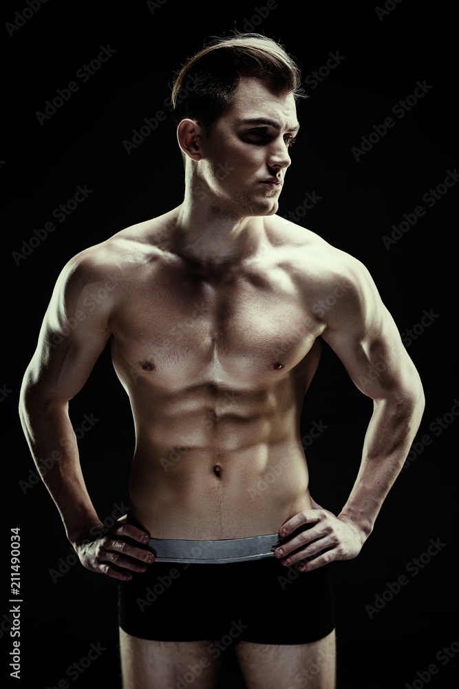 Fototapeta premium Handsome sporty young man in underwear posing on dark background