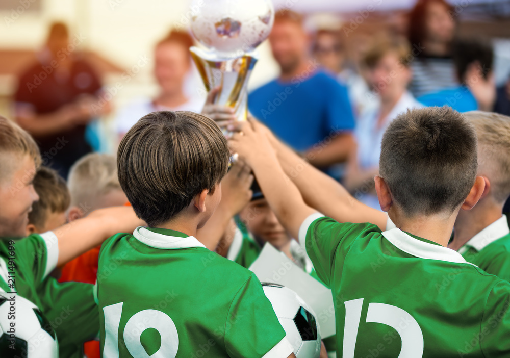 Fototapeta premium Kids Raising Golden Cup for Winning Sports Team. Children in Green Sportswear Celebrating Sport Success. Happy Kids Celebrate the Victory