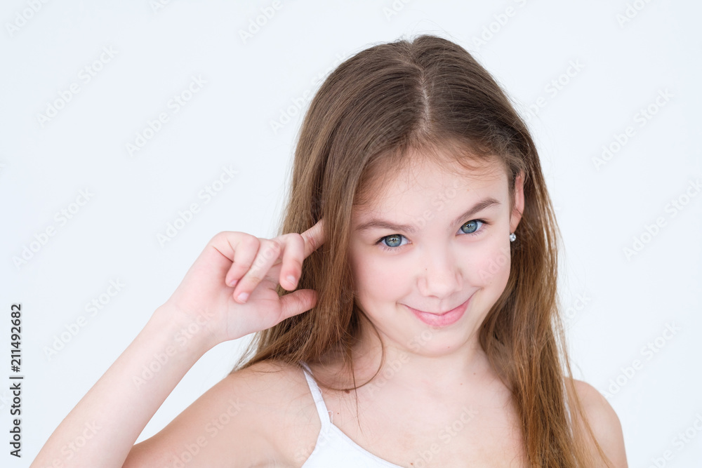 emotion face. child twisting finger at a temple judging you crazy. little girl portrait on white background. mood feelings personality and facial expression concept