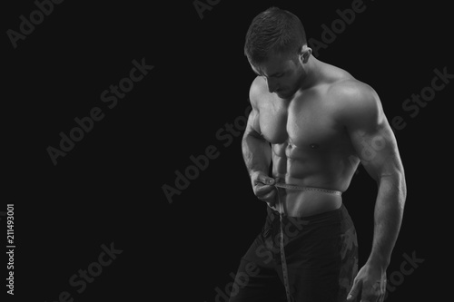 Strong muscular man measuring waist