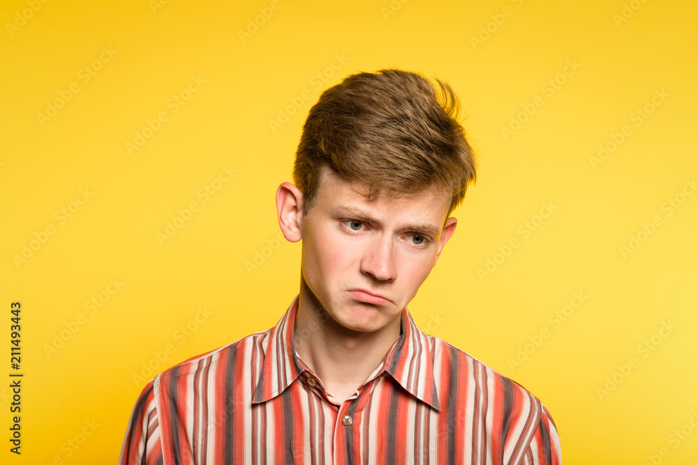 sad upset pensive disappointed crestfallen man. emotion facial expression and feelings. portrait of a young guy on yellow background. sad upset pensive disappointed crestfallen man. emotion facial expression and feelings. portrait of a young guy on yellow background.