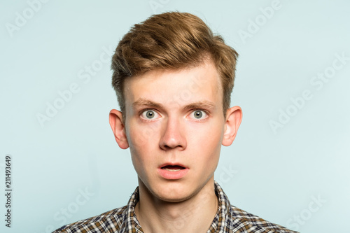 shocked speechless dumbstruck man with open mouth. portrait of a young guy on light background. emotion facial expression. feelings and people reaction.
