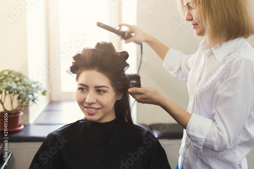 Hairstylist make curls on brown client's hair