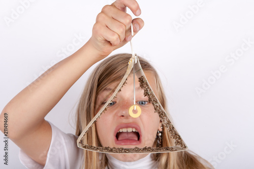 Shocked girl holding a moth trap full of trapped food moths photo