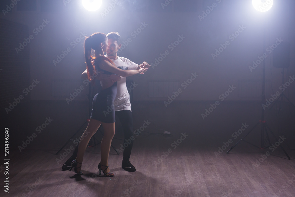 Skillful dancers performing in the dark room under the concert light and smoke. Sensual couple performing an artistic and emotional contemporary dance Skillful dancers performing in the dark room under the concert light and smoke. Sensual couple performing an artistic and emotional contemporary dance